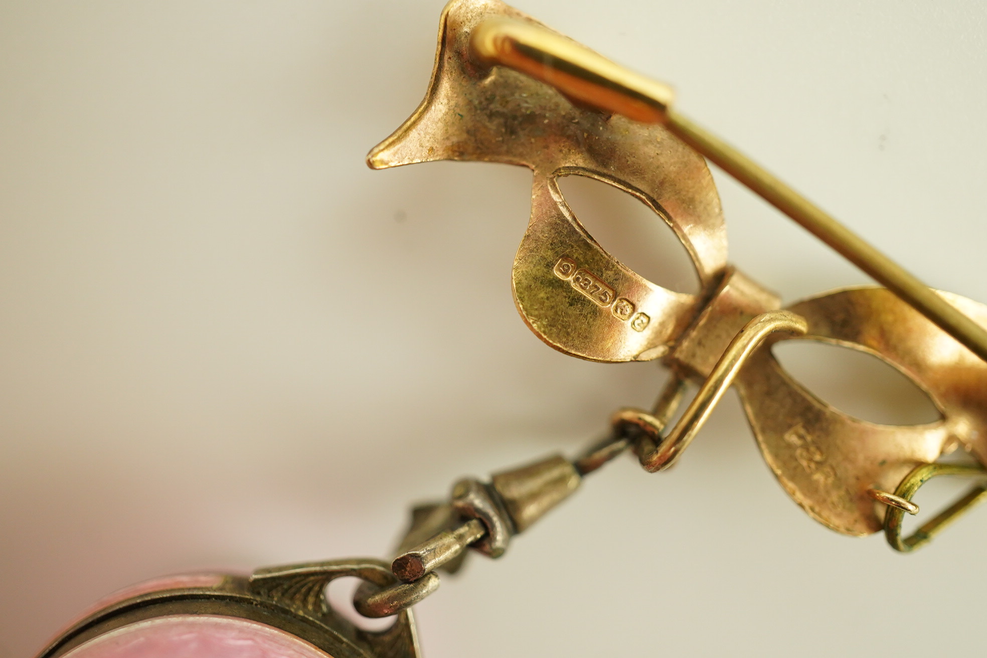 An early to mid 20th century silver and pink guilloche enamel Burger manual wind globe lapel watch, on a later 9ct gold ribbon bow suspension brooch